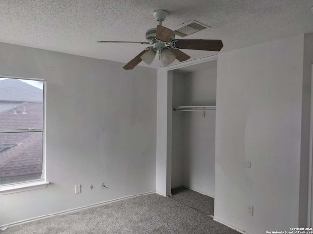 unfurnished bedroom with a textured ceiling, visible vents, a ceiling fan, a closet, and carpet