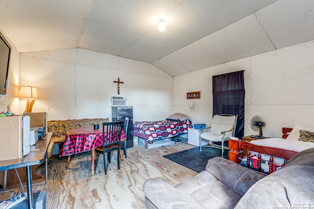 bedroom with a wall mounted air conditioner, vaulted ceiling, and wood finished floors