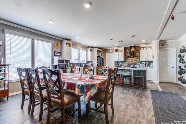 dining space with visible vents, crown molding, baseboards, and wood finished floors