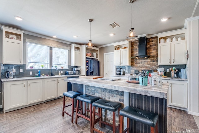 kitchen featuring open shelves, visible vents, white cabinets, wall chimney exhaust hood, and black fridge