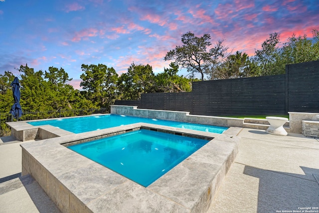 outdoor pool with a fenced backyard, a patio, and an in ground hot tub