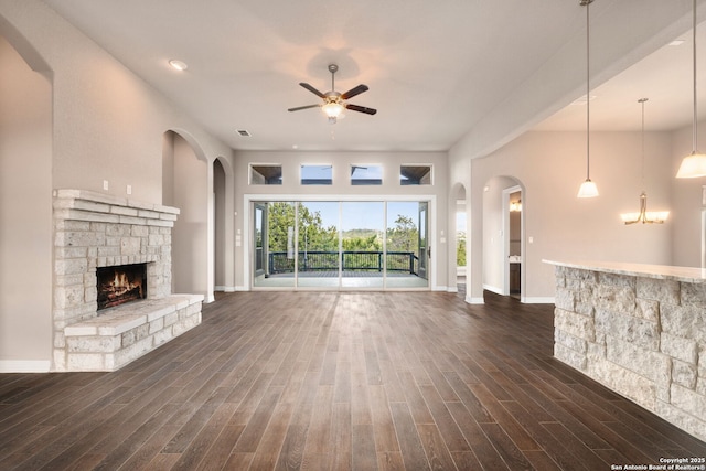 unfurnished living room featuring a fireplace, visible vents, a ceiling fan, baseboards, and dark wood-style floors