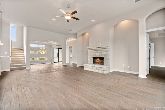 unfurnished living room featuring a ceiling fan, a fireplace, baseboards, and wood finished floors