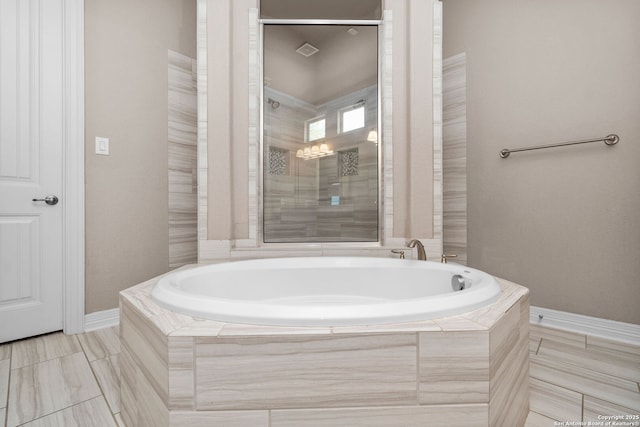 bathroom featuring a stall shower, baseboards, and a bath