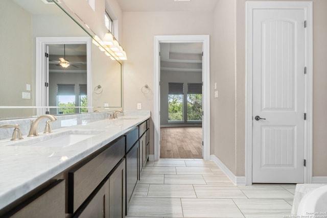 bathroom featuring double vanity, ceiling fan, baseboards, and a sink