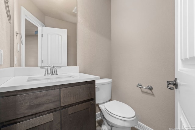 bathroom featuring baseboards, vanity, and toilet