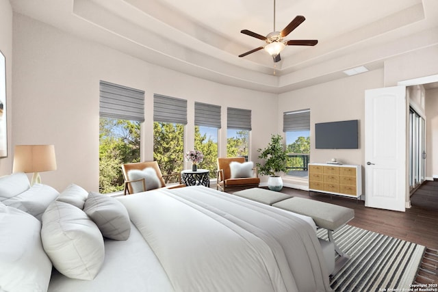 bedroom with a tray ceiling, dark wood-style flooring, visible vents, and a ceiling fan