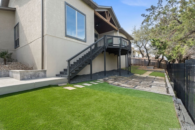 back of property featuring a deck, a fenced backyard, stairs, a lawn, and stucco siding