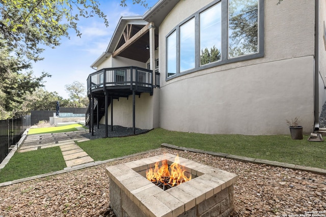 view of yard featuring an outdoor fire pit, a trampoline, fence, and a wooden deck