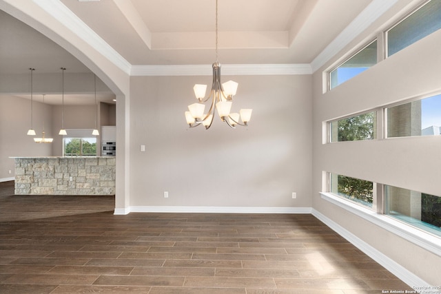 empty room with baseboards, a notable chandelier, a tray ceiling, and wood finished floors