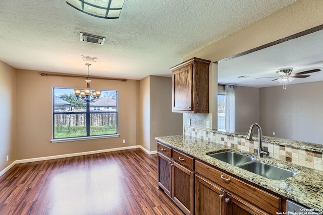 kitchen featuring dark wood finished floors, a sink, visible vents, and decorative backsplash