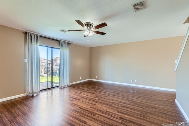 empty room featuring dark wood-style flooring, visible vents, and ceiling fan
