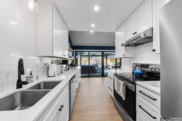 kitchen with under cabinet range hood, stainless steel appliances, a sink, white cabinets, and tasteful backsplash