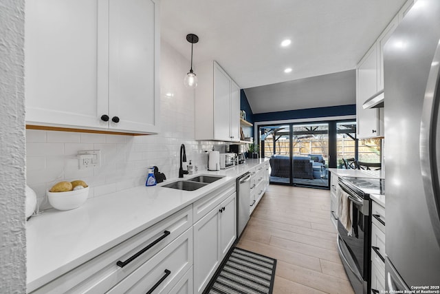 kitchen featuring a sink, white cabinets, light countertops, appliances with stainless steel finishes, and tasteful backsplash