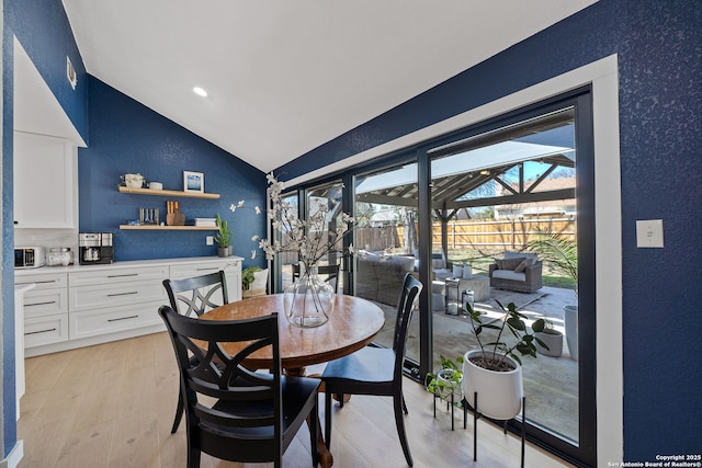 dining room featuring light wood-type flooring, a sunroom, vaulted ceiling, and recessed lighting