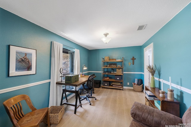 home office with wood finished floors, visible vents, and baseboards