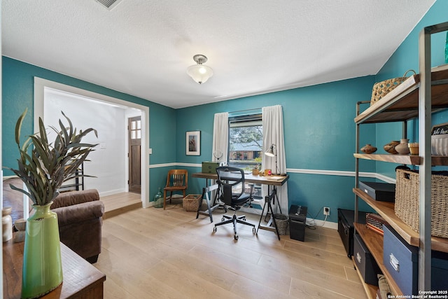 home office with a textured ceiling, wood finished floors, and baseboards