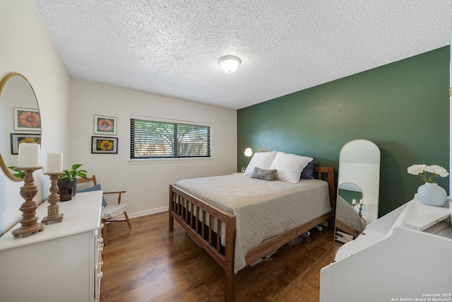 bedroom featuring a textured ceiling, baseboards, and wood finished floors