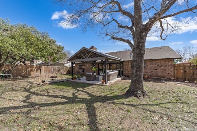 back of property with an outdoor hangout area, brick siding, a patio area, and a fenced backyard