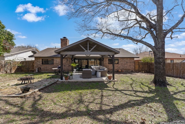 rear view of property with an outdoor living space with a fire pit, a gazebo, a patio area, and brick siding