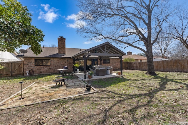 back of property featuring brick siding, a fenced backyard, a patio area, and an outdoor living space with a fire pit