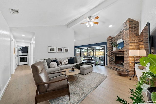 living area with light wood-type flooring, a brick fireplace, visible vents, and beamed ceiling