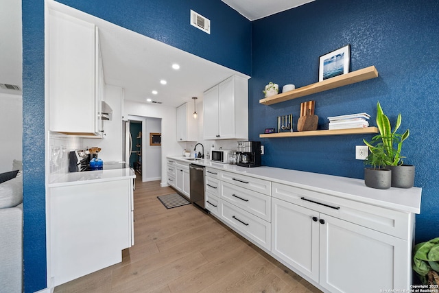 kitchen featuring stainless steel appliances, visible vents, light wood-style flooring, white cabinetry, and a sink