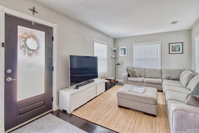 living room featuring dark wood-style floors, visible vents, and baseboards