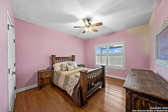 bedroom with ceiling fan, a textured ceiling, baseboards, and wood finished floors