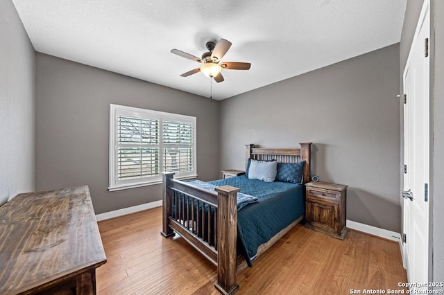 bedroom with ceiling fan, a textured ceiling, baseboards, and wood finished floors