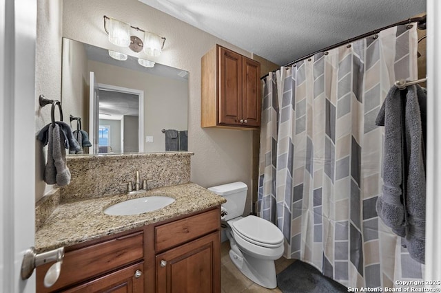 bathroom with toilet, vanity, a textured ceiling, and a textured wall