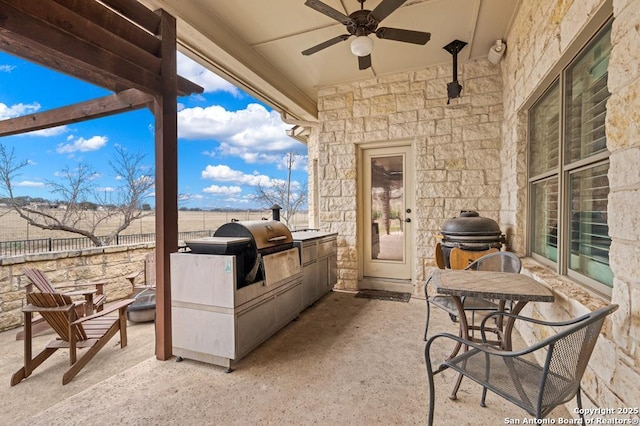 view of patio / terrace with exterior kitchen, grilling area, fence, and a ceiling fan