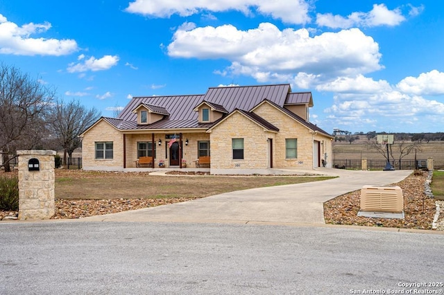 view of front of house featuring stone siding, a standing seam roof, fence, and metal roof