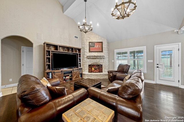 living room with arched walkways, visible vents, a stone fireplace, wood finished floors, and high vaulted ceiling