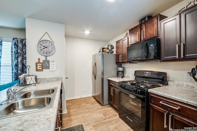 kitchen with black appliances, light wood-style floors, a sink, and light countertops