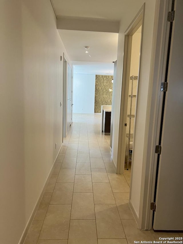 hallway featuring light tile patterned floors and baseboards