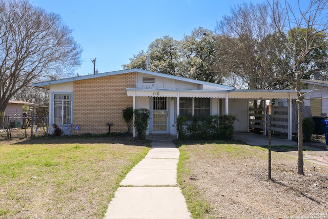 view of front of property featuring a carport, brick siding, a front lawn, and fence