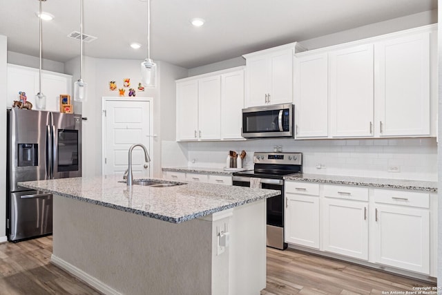 kitchen featuring stainless steel appliances, a sink, light wood finished floors, and tasteful backsplash