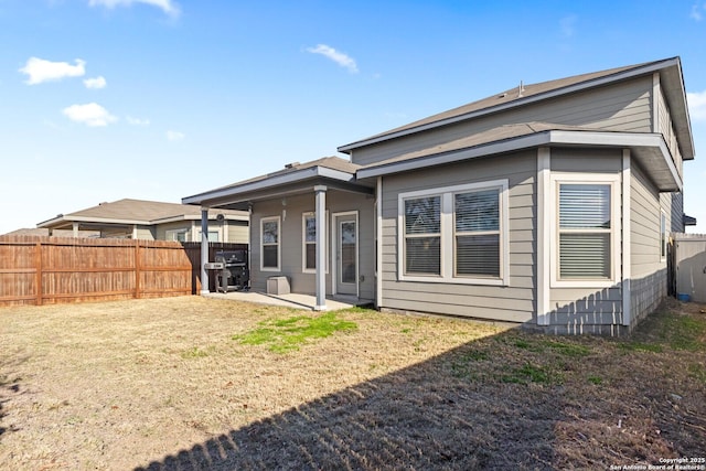 rear view of house with a lawn, a patio area, and fence