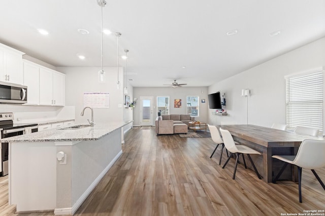 kitchen featuring a center island with sink, white cabinets, appliances with stainless steel finishes, light wood-type flooring, and a sink