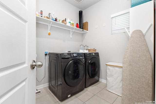 laundry room with laundry area, light tile patterned flooring, baseboards, and separate washer and dryer