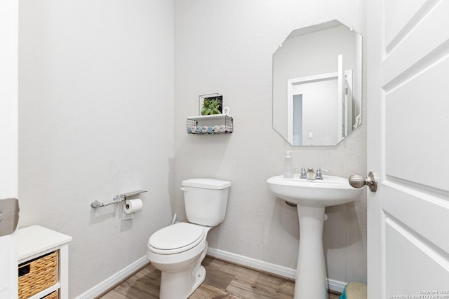 bathroom featuring baseboards, a sink, toilet, and wood finished floors