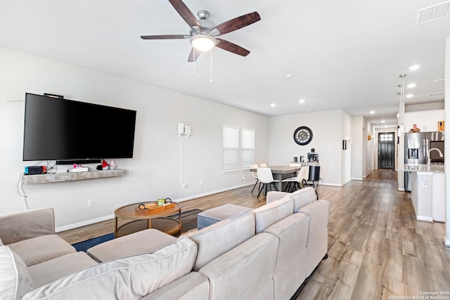 living area featuring baseboards, visible vents, and light wood-style floors