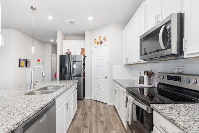 kitchen featuring tasteful backsplash, visible vents, appliances with stainless steel finishes, a sink, and light wood-type flooring