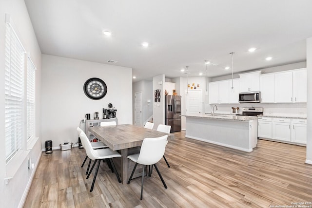 dining area with light wood finished floors, baseboards, visible vents, and recessed lighting