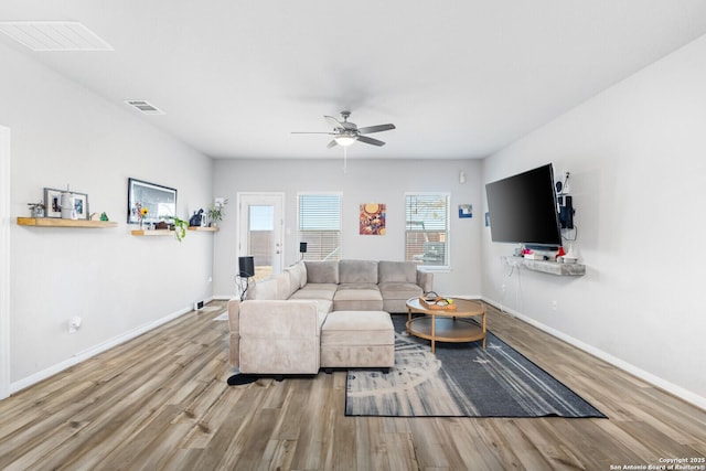 living room with a ceiling fan, wood finished floors, visible vents, and baseboards