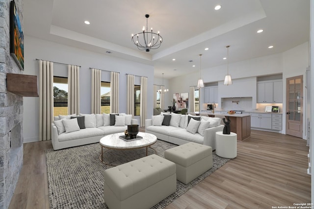 living room featuring a raised ceiling and an inviting chandelier