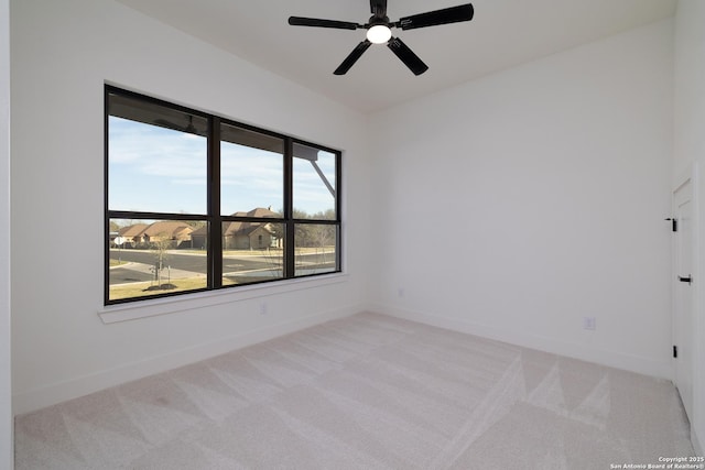 carpeted spare room with ceiling fan and baseboards