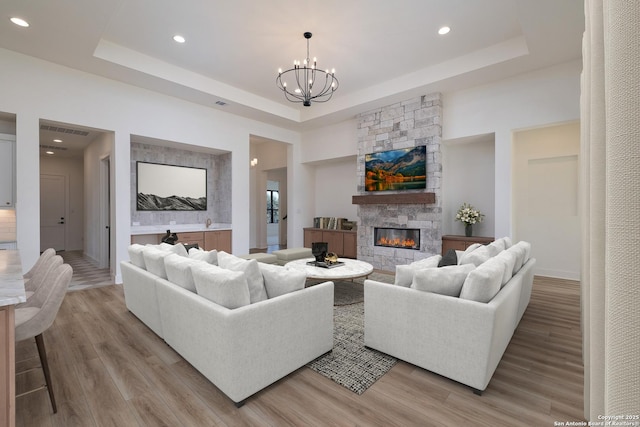 living room featuring light wood-type flooring, a chandelier, and a raised ceiling