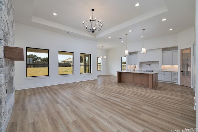 kitchen with an inviting chandelier, a tray ceiling, and open floor plan